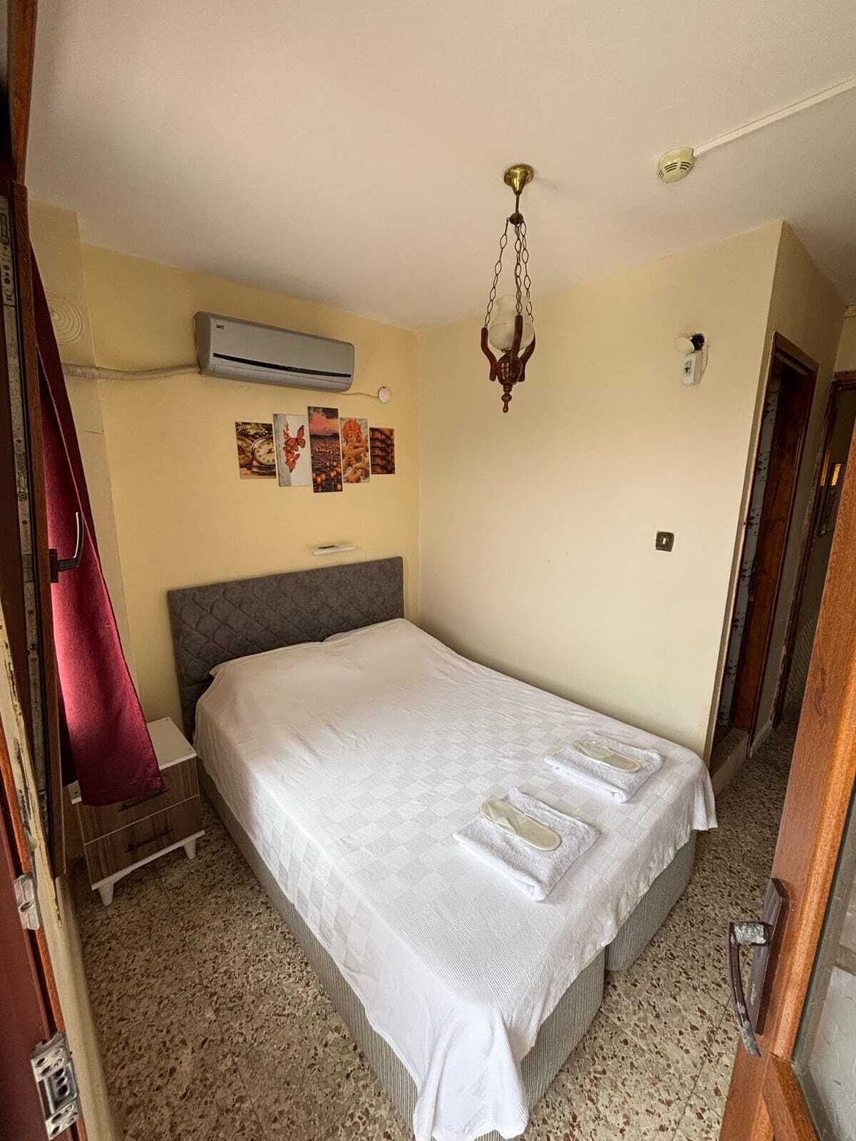 Une chambre d’hôtel équipée d’un lit, d’un climatiseur, d’un radiateur fixé au mur et d’une porte avec une poignée.
