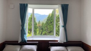 A room with two beds, a window with curtains, and a view of trees and mountains. - Private Room Guesthouse ORSA MINAMIASO (Minamiaso)
