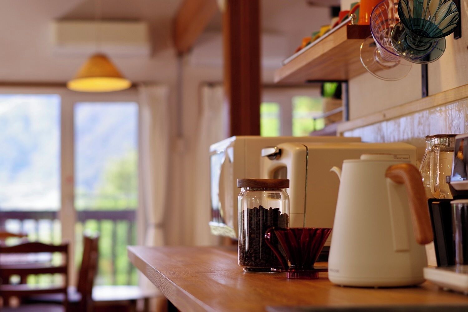 Une cuisine avec une machine à café, un bocal en verre et une tasse rouge posés sur un comptoir en bois.