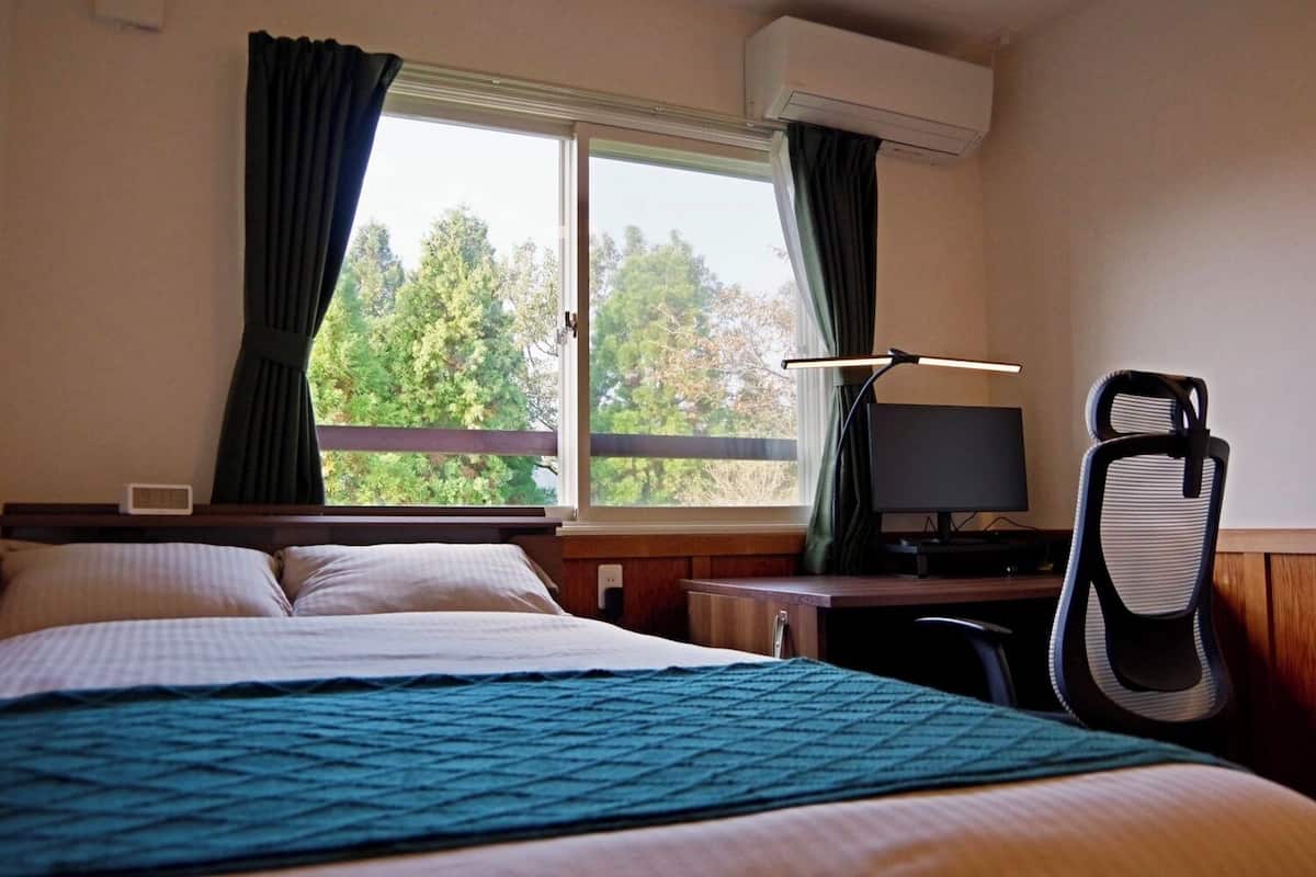A hotel room with a bed, a desk with a computer, and a chair.
