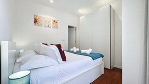 A modern bedroom with a bed, a bedside table, a lamp, and artwork on the wall. - Cityzen Funchal by Atlantic Holiday (Funchal)