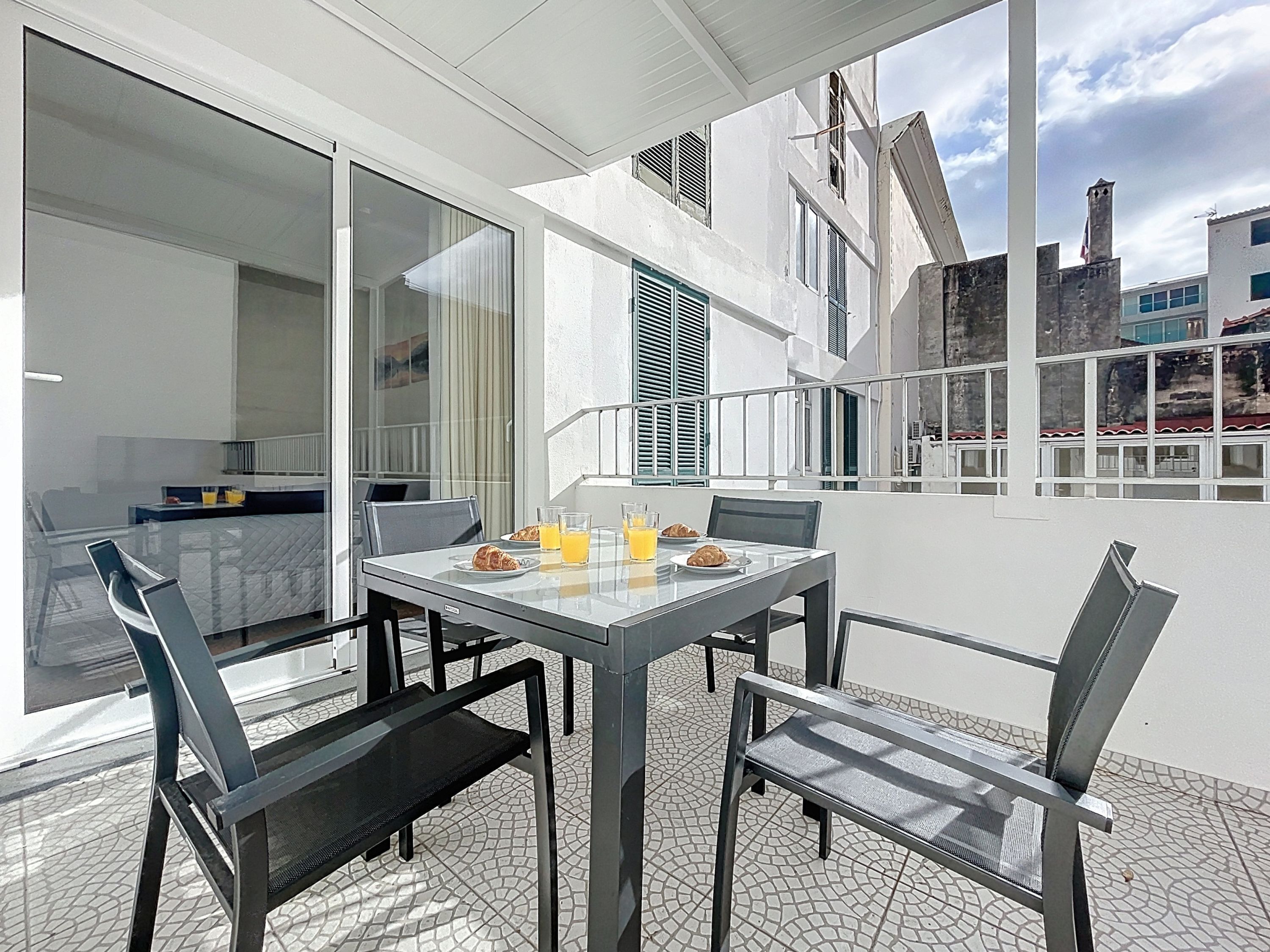 A balcony with a table set for breakfast, including croissants and orange juice.