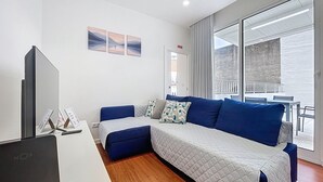 A modern bedroom with a sofa bed, a TV, and a balcony with a view. - Cityzen Funchal by Atlantic Holiday (Funchal)