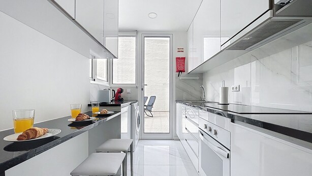 A modern kitchen with white cabinetry, a black countertop, and a view to the outside. - Cityzen Funchal by Atlantic Holiday (Funchal)