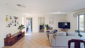 A spacious living area with a sofa, TV, and a wall-mounted photo display. - Entire Cozy 2-Bedroom House in Mount Waverley (Mount Waverley)