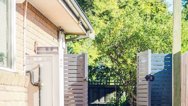 A pathway leading to a building with a brick facade, a water feature, and a tree-lined background. - Entire Cozy 2-Bedroom House in Mount Waverley (Mount Waverley)