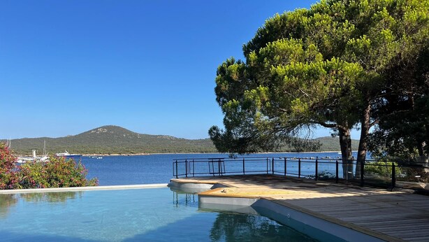 A clear swimming pool with a wooden deck and a view of the sea and distant hills. - Anchored in a privileged spot 15mn Figari, Bonifacio,Roccapina,Sperone,Murtoli (Pianottoli-Caldarello)