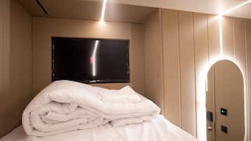 Une chambre d’hôtel équipée d’un lit, d’un téléviseur à écran plat fixé au mur et d’une porte dotée d’un écran numérique.