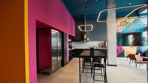 Una cucina moderna con un frigorifero capiente, un'area pranzo con sgabelli e un muro colorato con graffiti.
