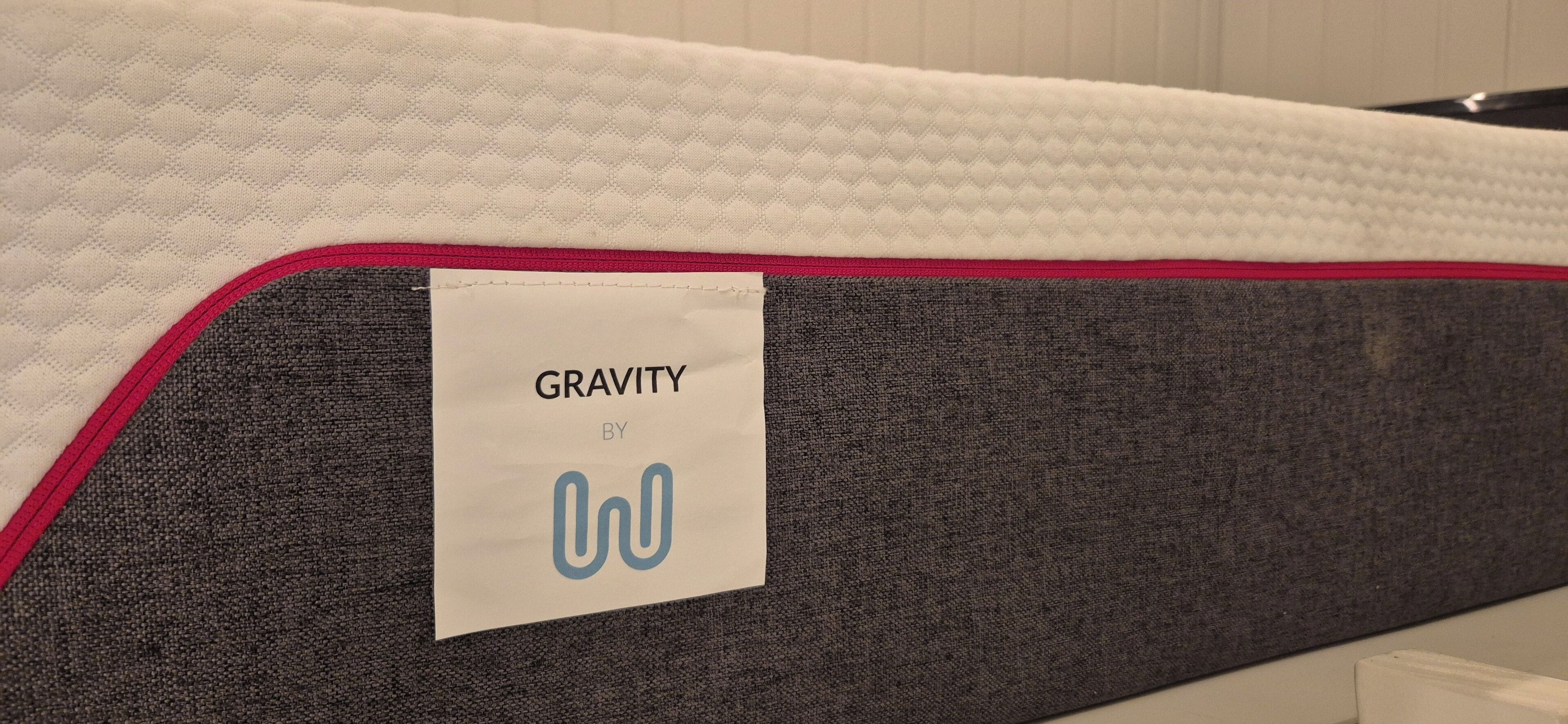 Eine Matratze mit einem Etikett, auf dem “GRAVITY BY” steht, und einem Logo.