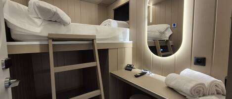A bunk bed room with a desk, a mirror, and a towel.