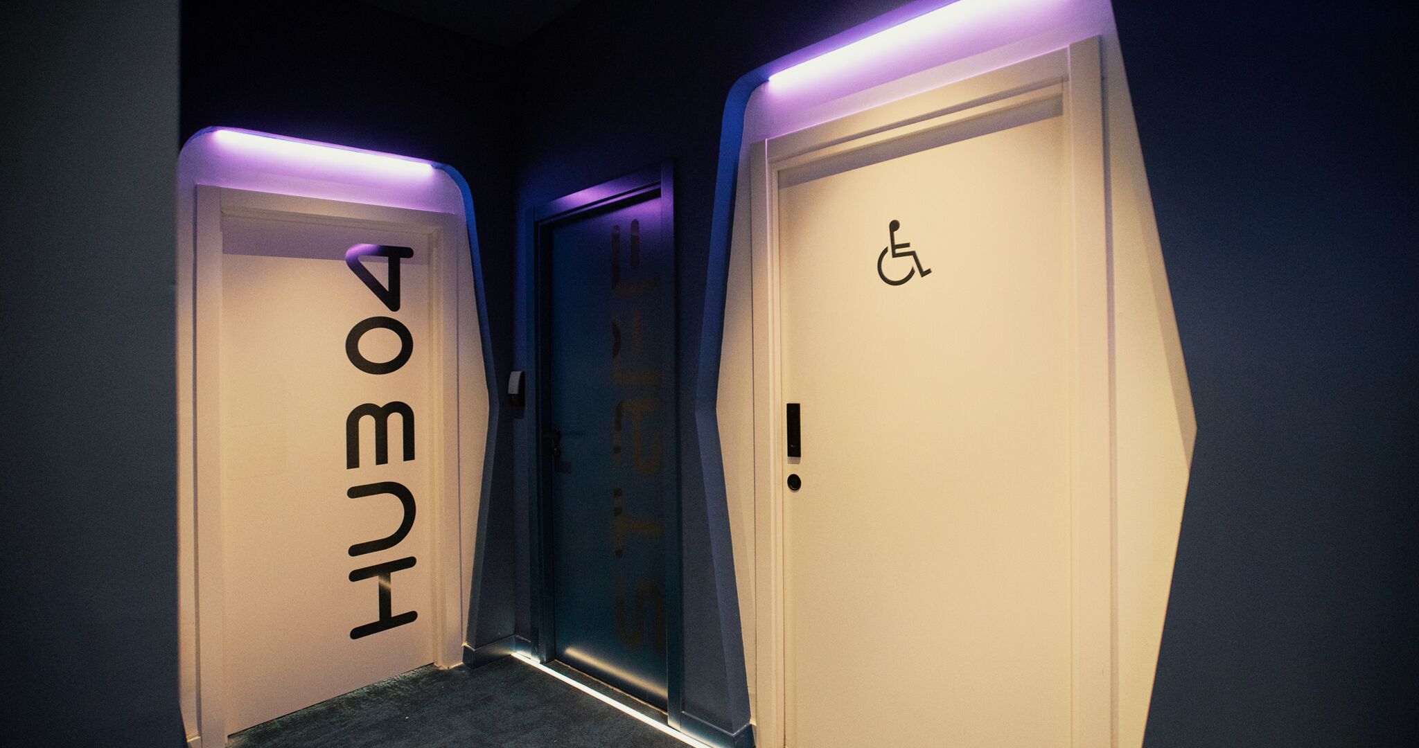 Ein Flur mit zwei Türen, eine beschriftet mit 'VOMITI' und die andere mit einem Rollstuhlgerechtigkeitszeichen.