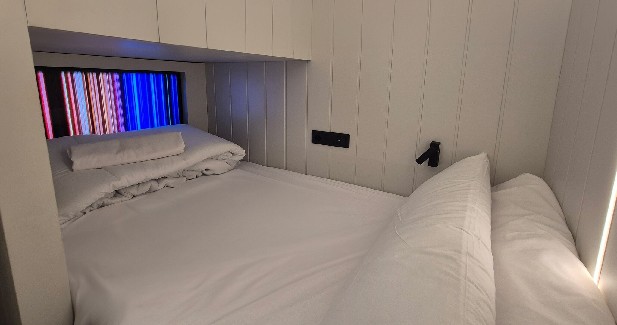 Une chambre moderne avec un lit, un téléviseur intégré et un panneau de commande situé près du lit.