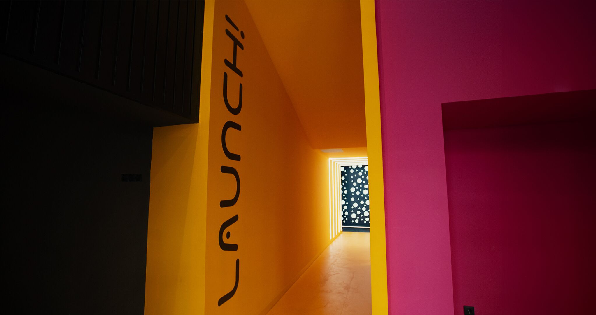 Un pasillo bien iluminado, con una pared amarilla y una pared rosa a la derecha.