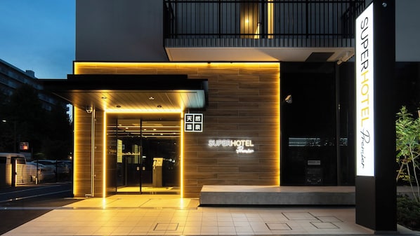 A modern hotel entrance with a prominent sign reading "SUPERHOTEL Premier".