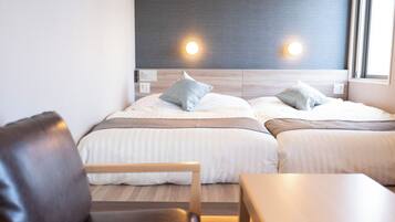 A double bed with two pillows, a bedside table, a chair, and a window with natural light.