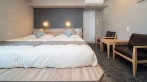 Ein modernes Hotelzimmer mit einem großen Bett, zwei Nachttischen, einem Sessel und einer Klimaanlage.