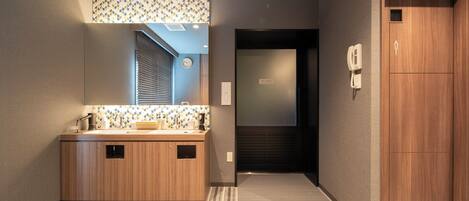 A modern bathroom with a wooden vanity, a mirror, and a patterned wall.
