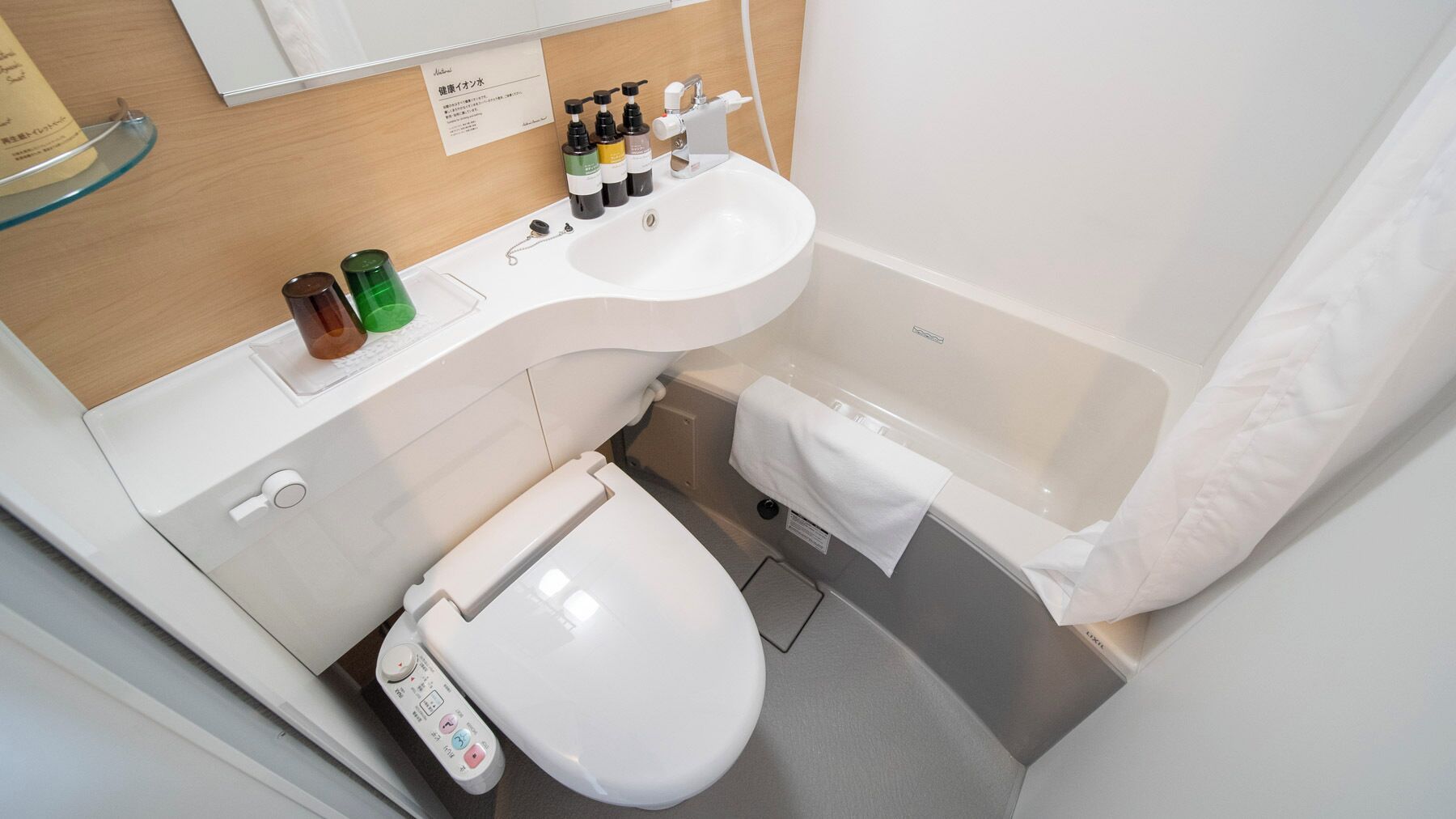 A modern bathroom with a white sink, toilet, and bathtub. There are toiletries on the sink counter.