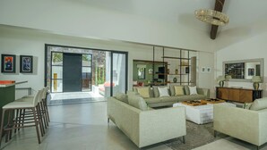 A spacious living area with a sofa set, a coffee table, and a dining area with chairs.
