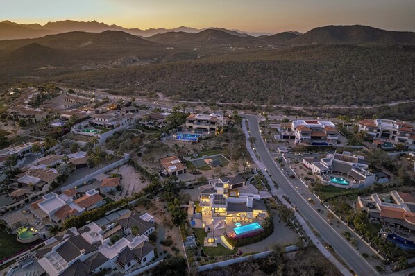 An aerial view of a residential area with houses, roads, and a large building with a swimming pool.