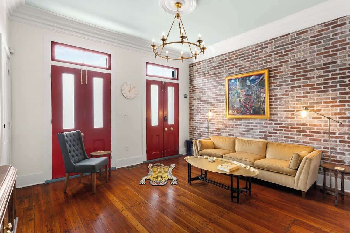 A living room with a brick wall, a chandelier, a sofa, and a chair.