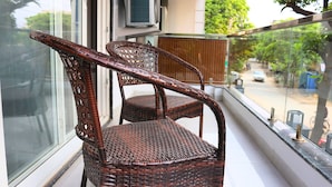 Two wicker chairs on a balcony with a view of a street and trees. - Fuji Ryokan Corporate Stays (Gurugram)