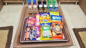A room with a brown leather chair, a tray of snacks, and water bottles on the floor. - Hello Banaras (Varanasi)