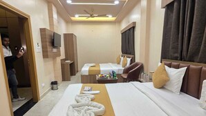 A hotel room with a large bed, a ceiling fan, a TV, and a minibar. - Hello Banaras (Varanasi)