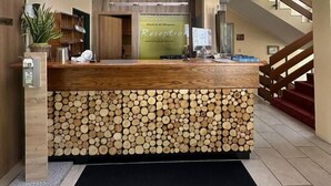 Ein Empfangstresen mit Holzbeschichtung und einer Basis aus Baumstämmen, darüber ein Oberlicht und eine Treppe zur Rechten.