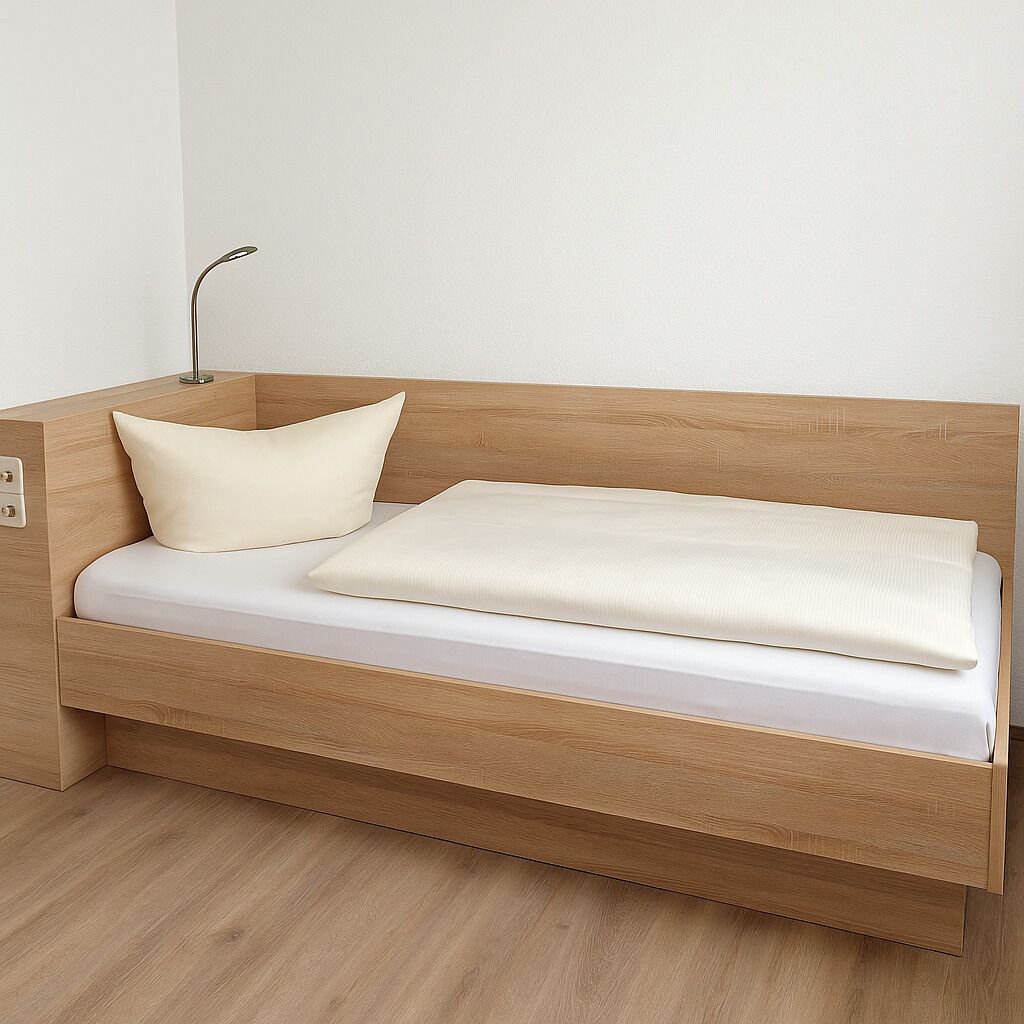 A wooden bed with a white mattress and a single cream-colored pillow.