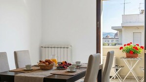Ein Balkon mit einem Frühstückstisch, einem Heizkörper und Blick auf Gebäude und Berge.