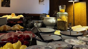 Um buffet de café da manhã com diversas opções de comida, incluindo frutas, doces e laticínios.