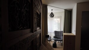 Quarto de hotel com cama, uma cadeira, uma mesinha, abajur e armário.