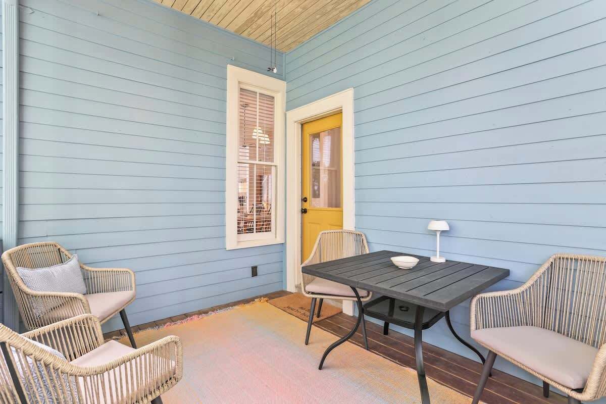 Un patio couvert avec une table et des chaises, une porte et une fenêtre avec des stores.