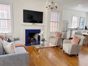 A modern living room with a fireplace, a television, and a dining area.