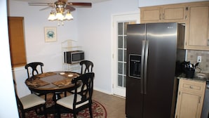 A kitchen with a refrigerator, microwave, and wooden cabinets. - Navarre Beach Escape-Pet & Family Friendly (Navarre)