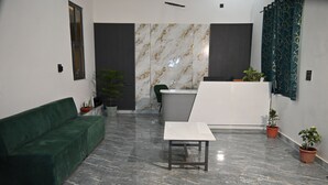 Un espace d’accueil moderne avec un canapé vert, une table blanche et un comptoir de réception.