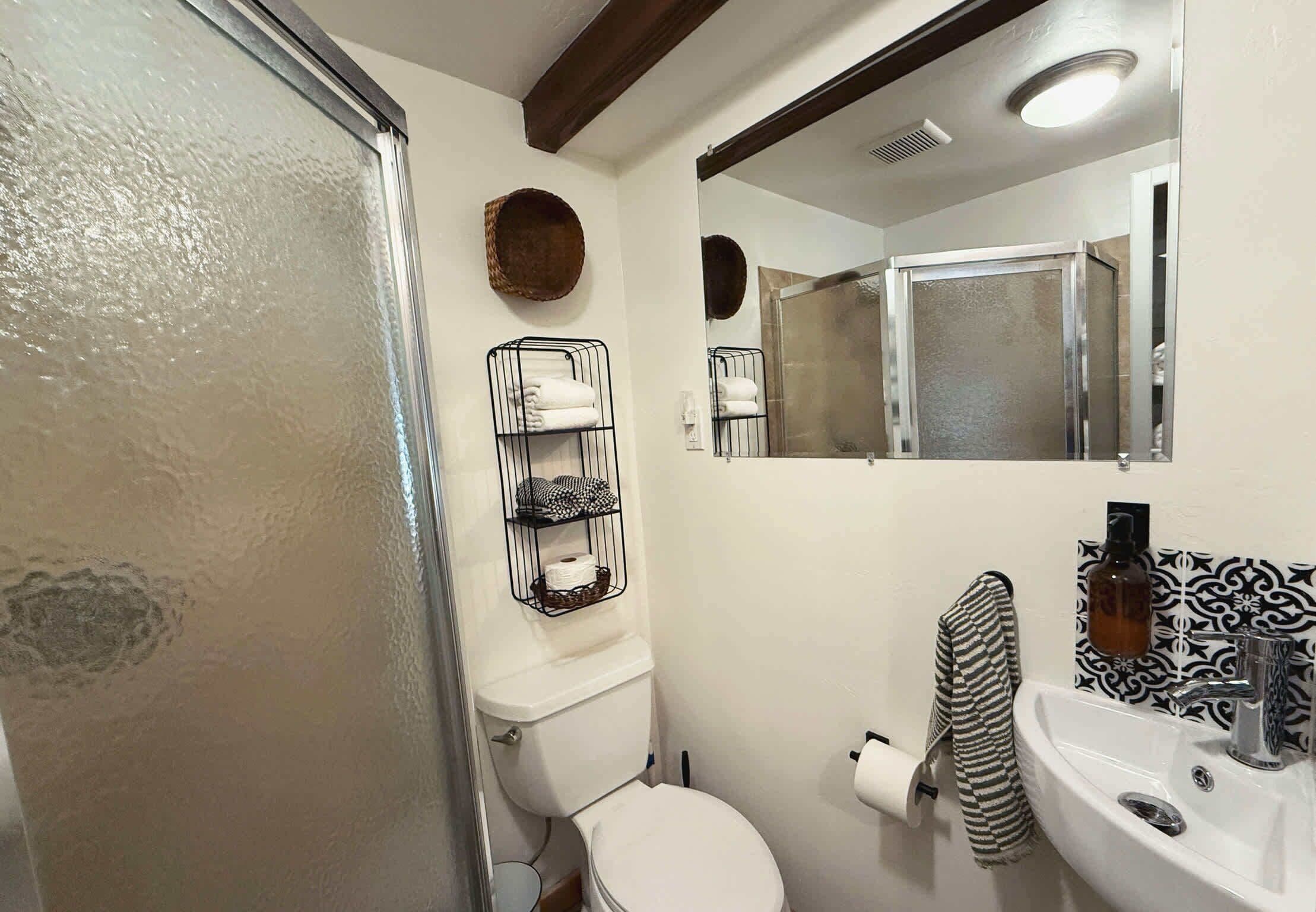 Een badkamer met toilet, wastafel, douche en spiegel.