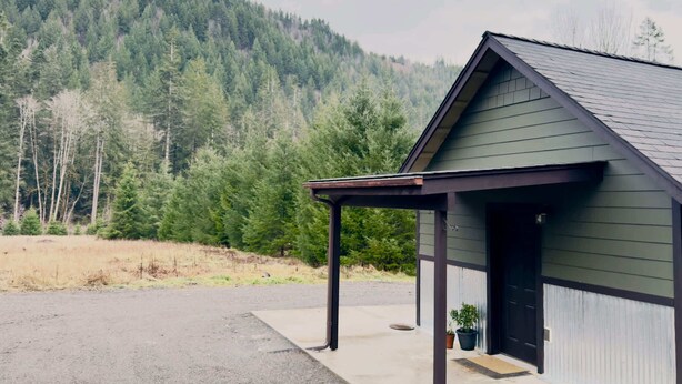 Un bâtiment d’un seul étage, doté d’un toit en pente, d’un porche couvert et d’une porte noire.