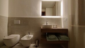 Ein modernes Badezimmer mit einer Bidet, einem Waschbecken und einem Spiegel.