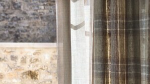 A wicker chair, a table, and a stone wall. - Hotel Maison Turenne (Martel)