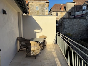 Een balkon met rieten meubilair, een betegelde vloer en een stenen muur.