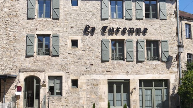 A stone building with the name 'La Turenne' on the facade, featuring multiple windows with shutters, a central entrance, and a small porch area. - Hotel Maison Turenne (Martel)