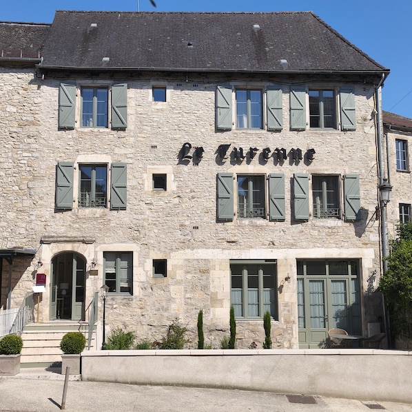 A stone building with the name 'La Turenne' on the facade, featuring multiple windows with shutters, a central entrance, and a small porch area. - Hotel Maison Turenne (Martel)