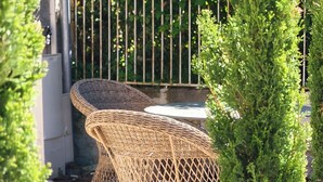 Wicker outdoor furniture, a paved patio, and a metal fence. - Hotel Maison Turenne (Martel)