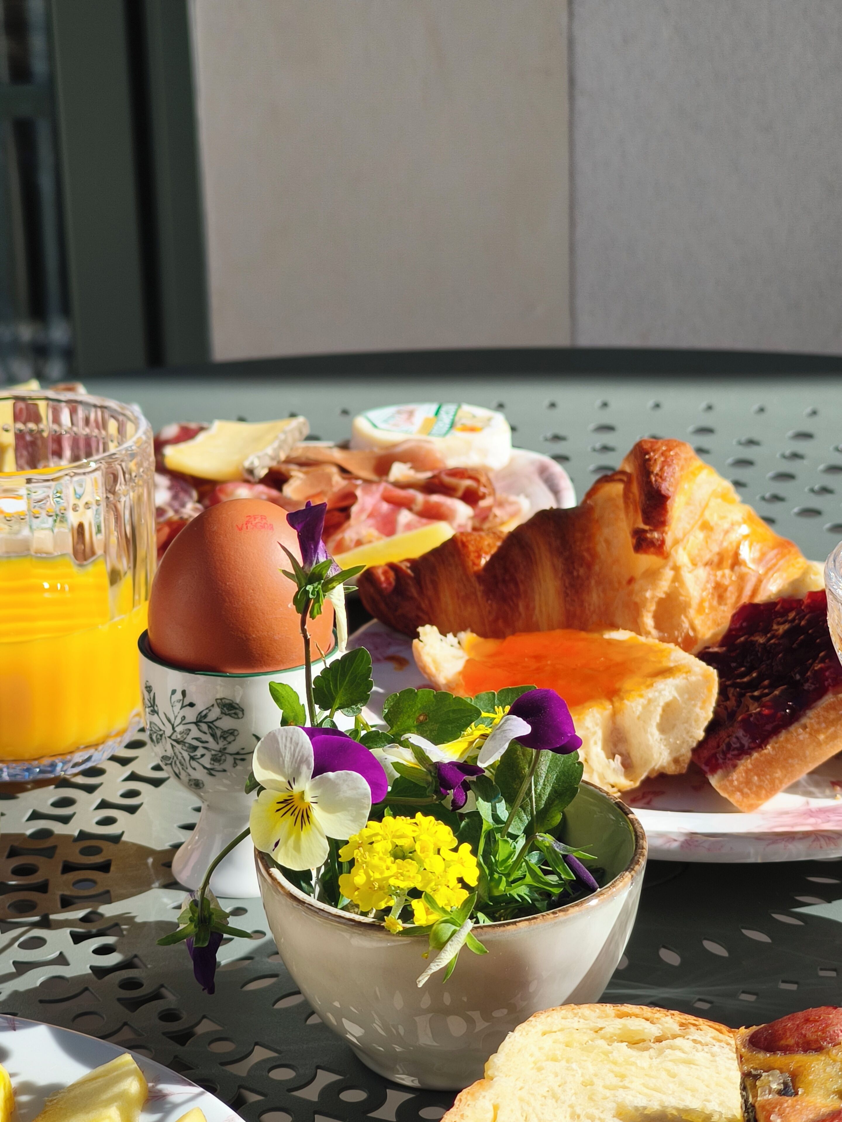A breakfast setting with eggs, bread, and a flower arrangement on a table.
