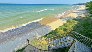 Une plage avec un escalier en bois descendant jusqu’au rivage, une plage de sable et l’océan.
