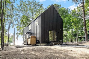 Una cabaña moderna de madera con techo inclinado, ventanas amplias y puerta de madera.