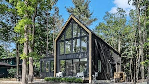 Una cabaña de madera moderna con ventanas amplias, rodeada de árboles.